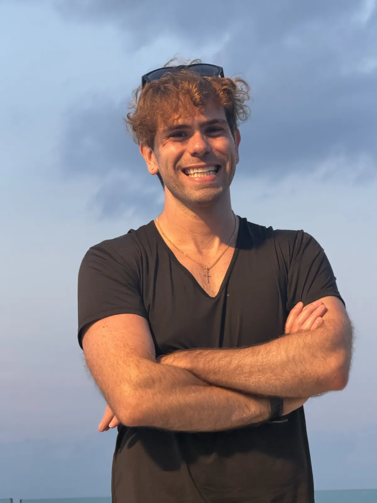 Nick grinning with arms crossed against a golden-hour sky