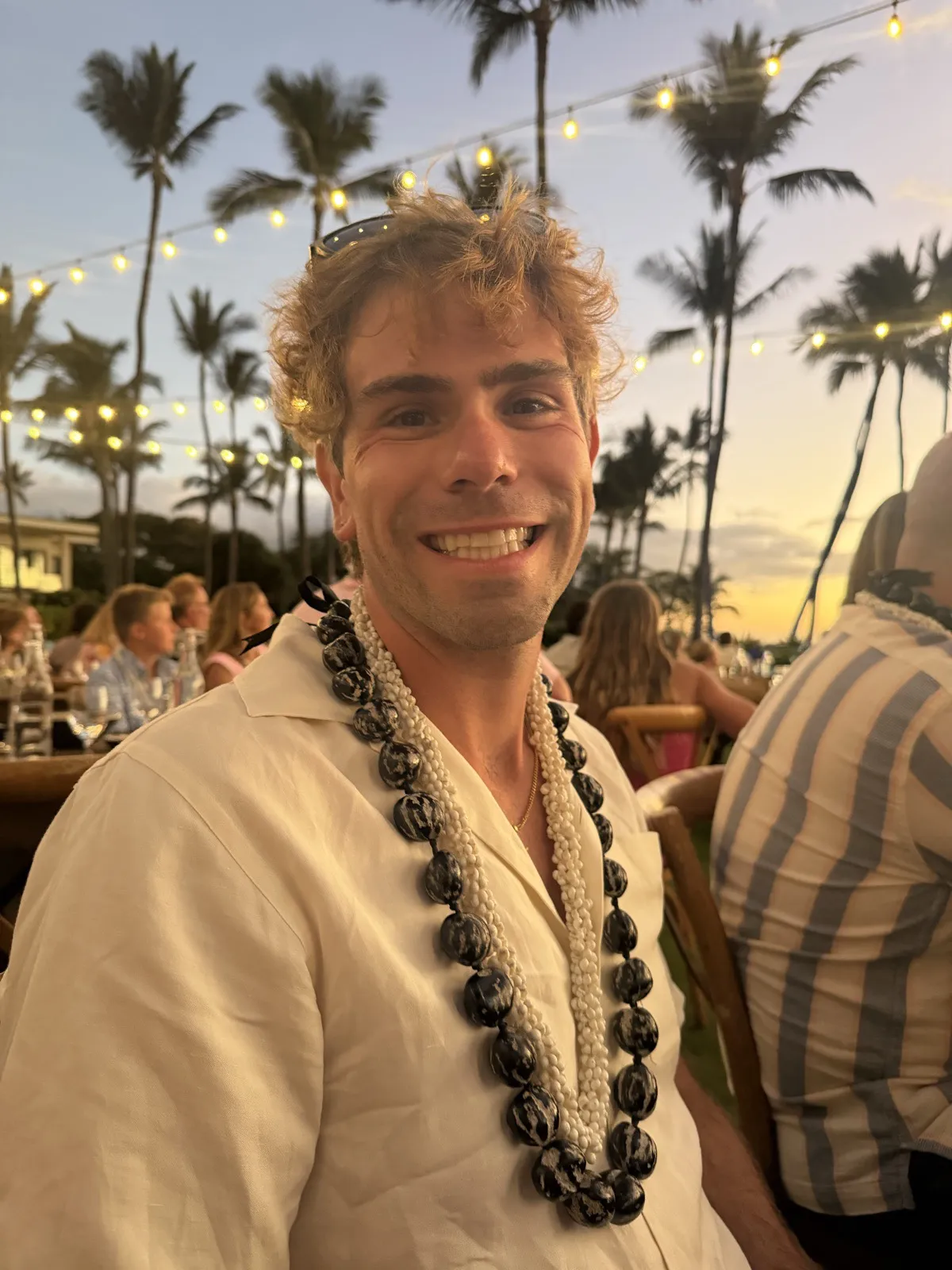 Nick smiling in a lei at a sunset luau